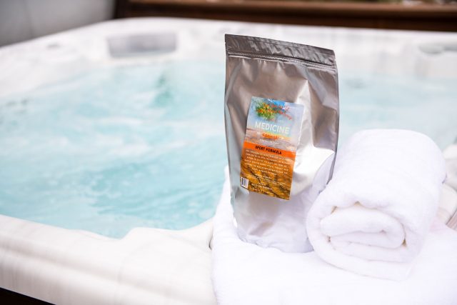 A pouch of Medicine Springs Sport Formula mineral therapy product sitting on the edge of a hot tub.